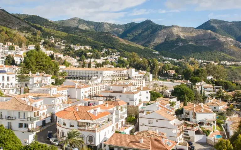 Mijas Pueblo from the air with mountains to the background and cloudy sky.
