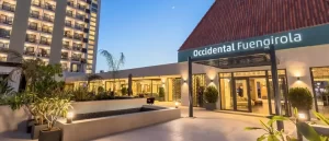 Exterior view of Barcelo Occidental Hotel in Fuengirola at dusk, featuring illuminated entrance and modern architecture.