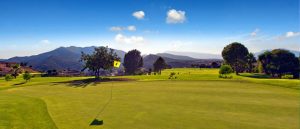 The 4th hole at Alhaurin Golf with mountains in the distance and an almost clear blue sky.