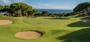 Scenic view of Cabopino Golf course with lush green fairways, sand bunkers, and ocean backdrop.
