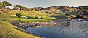 One of the holes on the La Cala Asia course with a lake with fountain in the foreground and roling hills in the background.