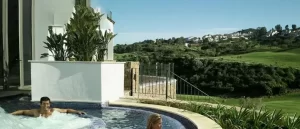 Relaxing outdoor jacuzzi at La Cala Resort in Mijas Costa, with guests enjoying the warm water and a scenic view of the lush green golf course and distant hillside villas.