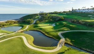 Golf course landscape with winding paths, water features, and a view of the ocean, representing La Hacienda links course.