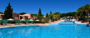 Swimming pool at the Pestana Vila Sol in Vilamoura with empty sunbeds and blue sky.