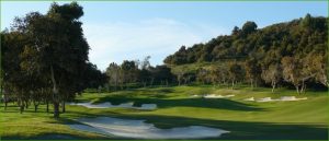 View of Santana Golf course with sand bunkers, lush green fairways, and surrounding trees under a clear blue sky.