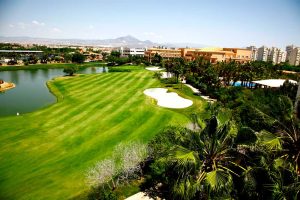 One of the fairways at Alicante Golf with lake to the left, green and mountains in the distance.