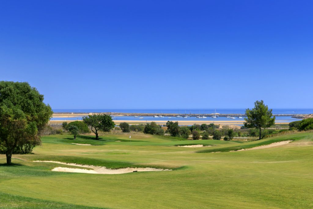 One of the greens at the Palmeras course with boats moored up in the background and the sea and blue sky.