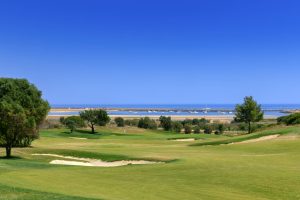 One of the greens at the Palmeras course with boats moored up in the background and the sea and blue sky.
