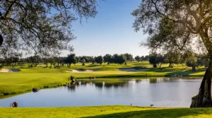 A lovely view of the Quinta da Ria golf course with a lake in the foreground with a green surrounded by bunkers in the background.
