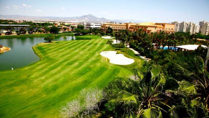 One of the fairways at Alicante Golf with lake to the left, green and mountains in the distance.