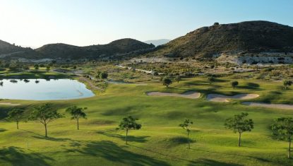 Font del Llop golf course with a lake to the left and surrounded by small mountains in the background.