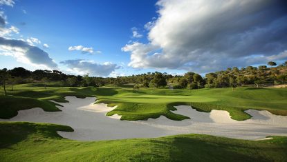 Las Colinas golf course green with large bunkers in the foreground and a cloudy sky.