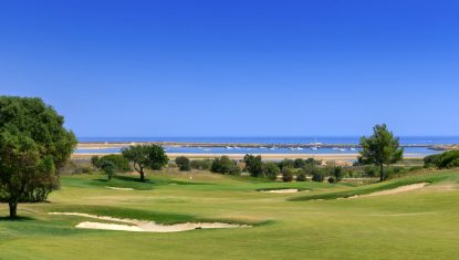 One of the greens at the Palmeras course with boats moored up in the background and the sea and blue sky.