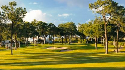 One of the beautiful greens at Pinheiros Altos surrounded by pine trees with a slightly cloudy sky.