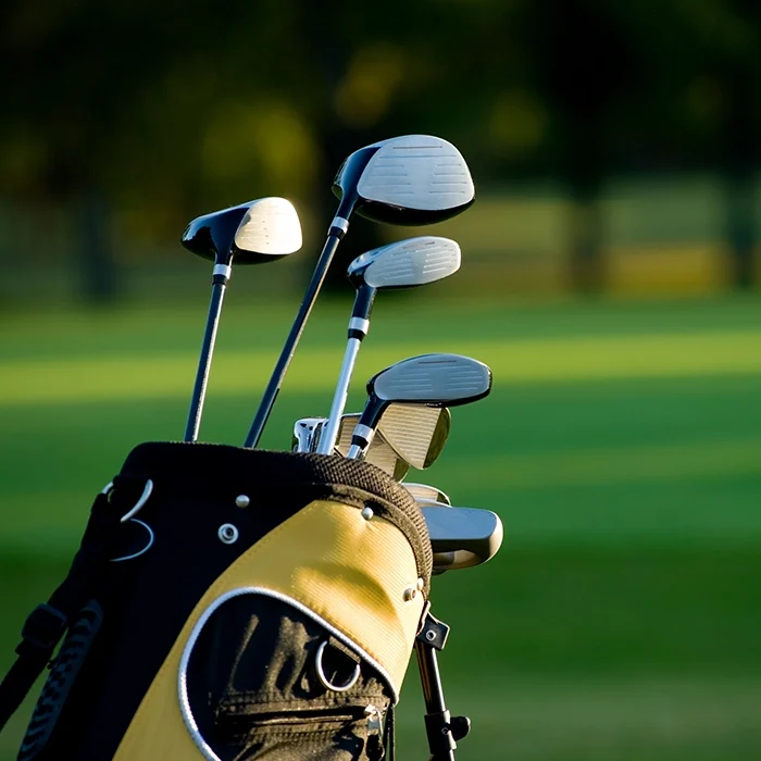 A yellow and black golf bag with some golf clubs.