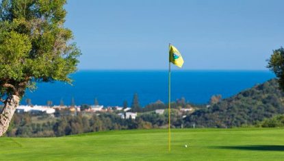 A green at Estepona Golf with a golf ball sitting near the pin and the gorgeous blue Mediterranean Sea in the background.