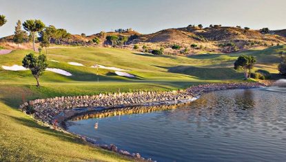One of the holes on the La Cala Asia course with a lake with fountain in the foreground and roling hills in the background.