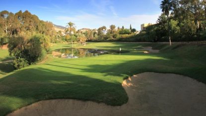 A green at La Quinta golf with a bunker to the front lake behind and a clear blue sky.