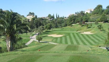 A tee at the Los Arqueros Golf course with palm tree to the left and blue sky.