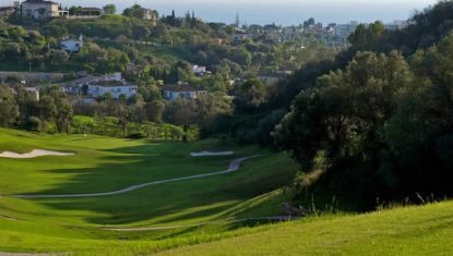 View of one of the holes at Marbella Golf and Country Club with a lush green fairway, the green to the distance and views of the Mediterranean Sea.