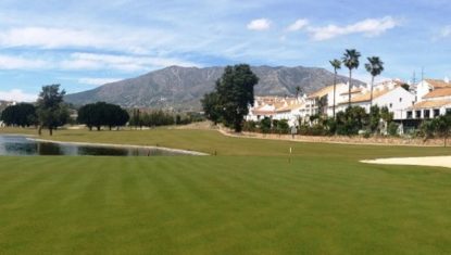 The Mijas Los Lagos course with lake to the left, residential properties to the right and mountain to the distance.