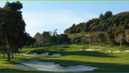 View of Santana Golf course with sand bunkers, lush green fairways, and surrounding trees under a clear blue sky.